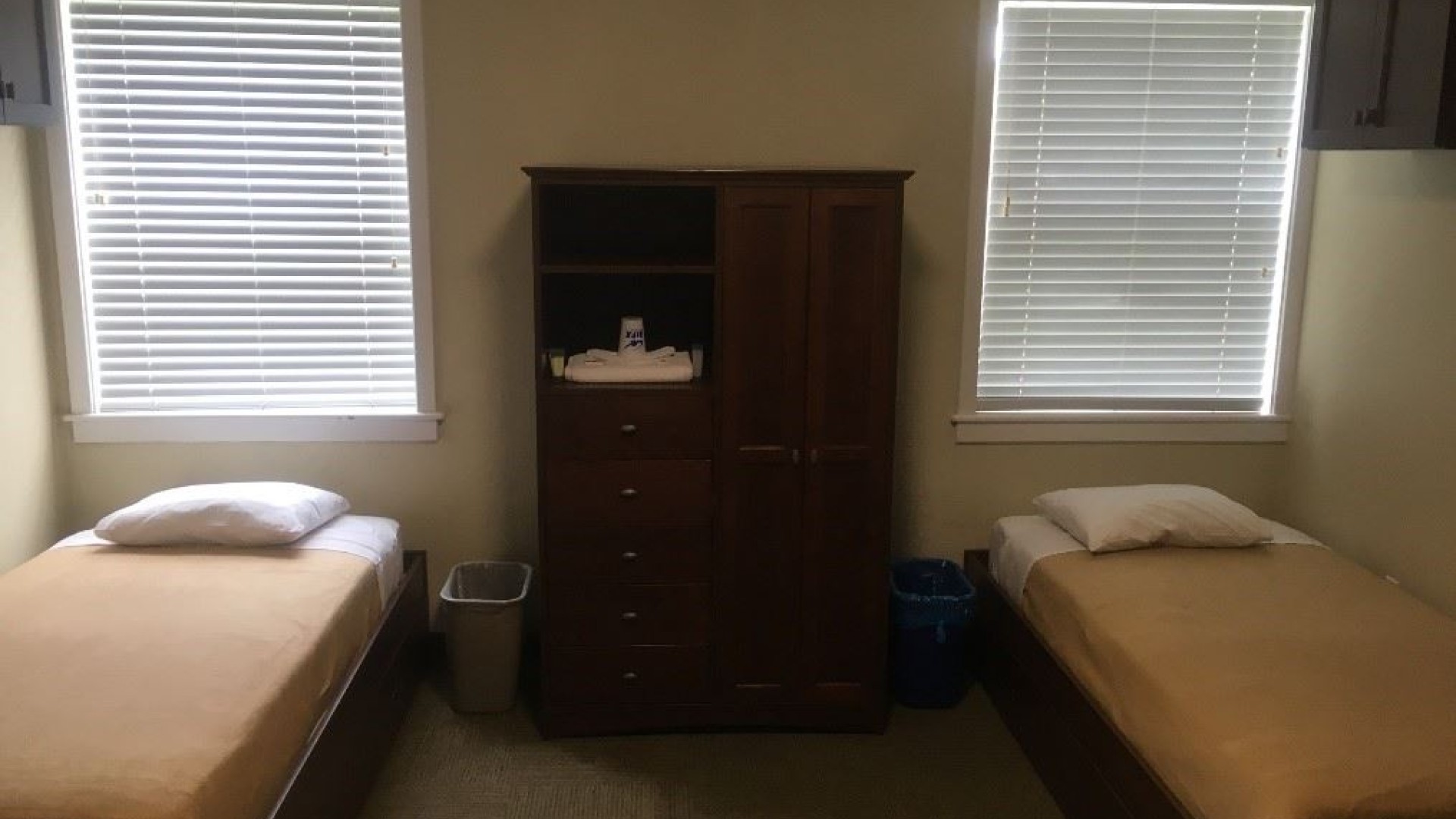 Two beds with windows above each in a double room.