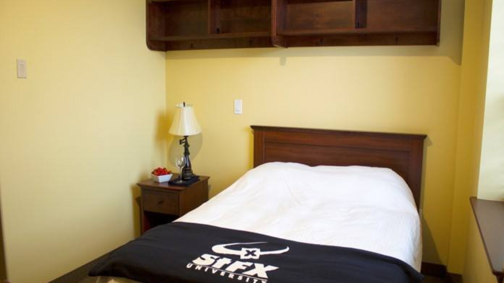 Governors Hall single suite with a double bed and bedside table.