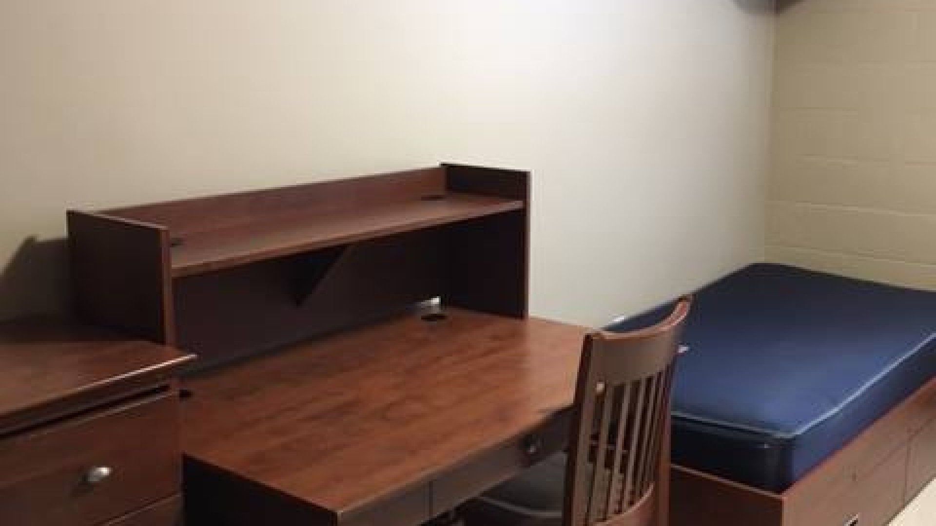 One side of a double room with bed, desk and storage 