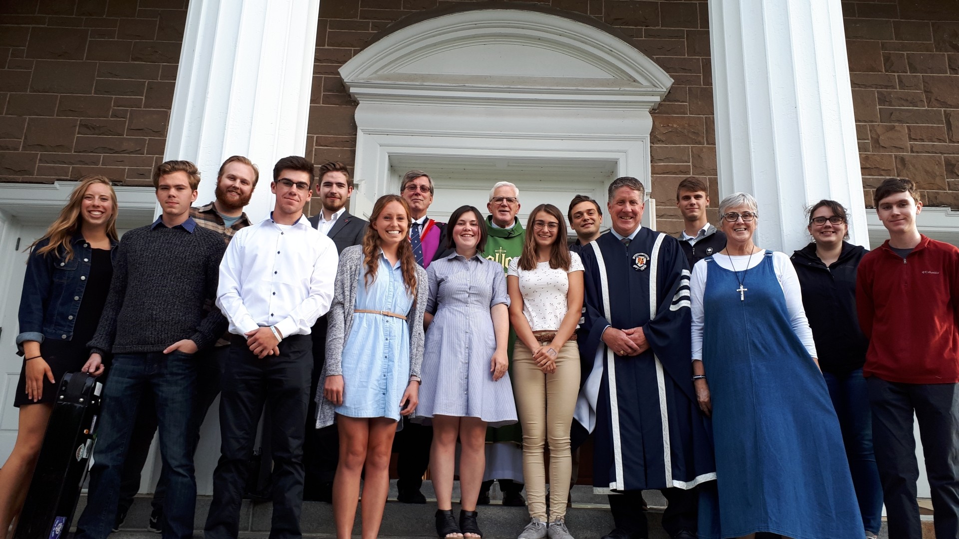 A group of people standing in front of a church entrance smiling
