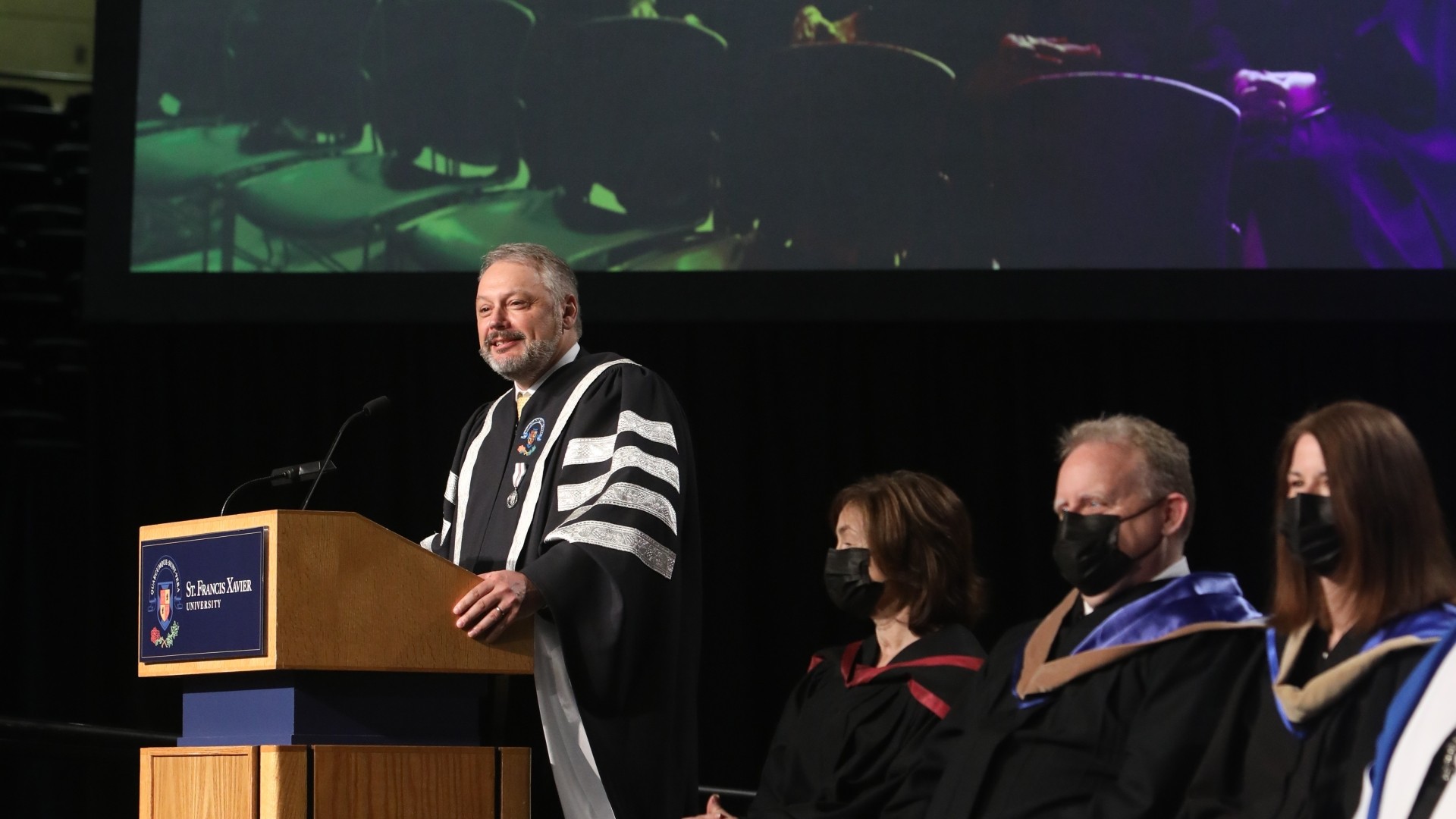 Dr. Andy Hakin speaking at a podium