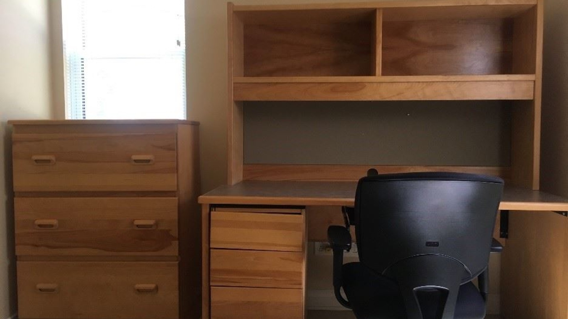 Desk and dresser located in an apartment style single room.