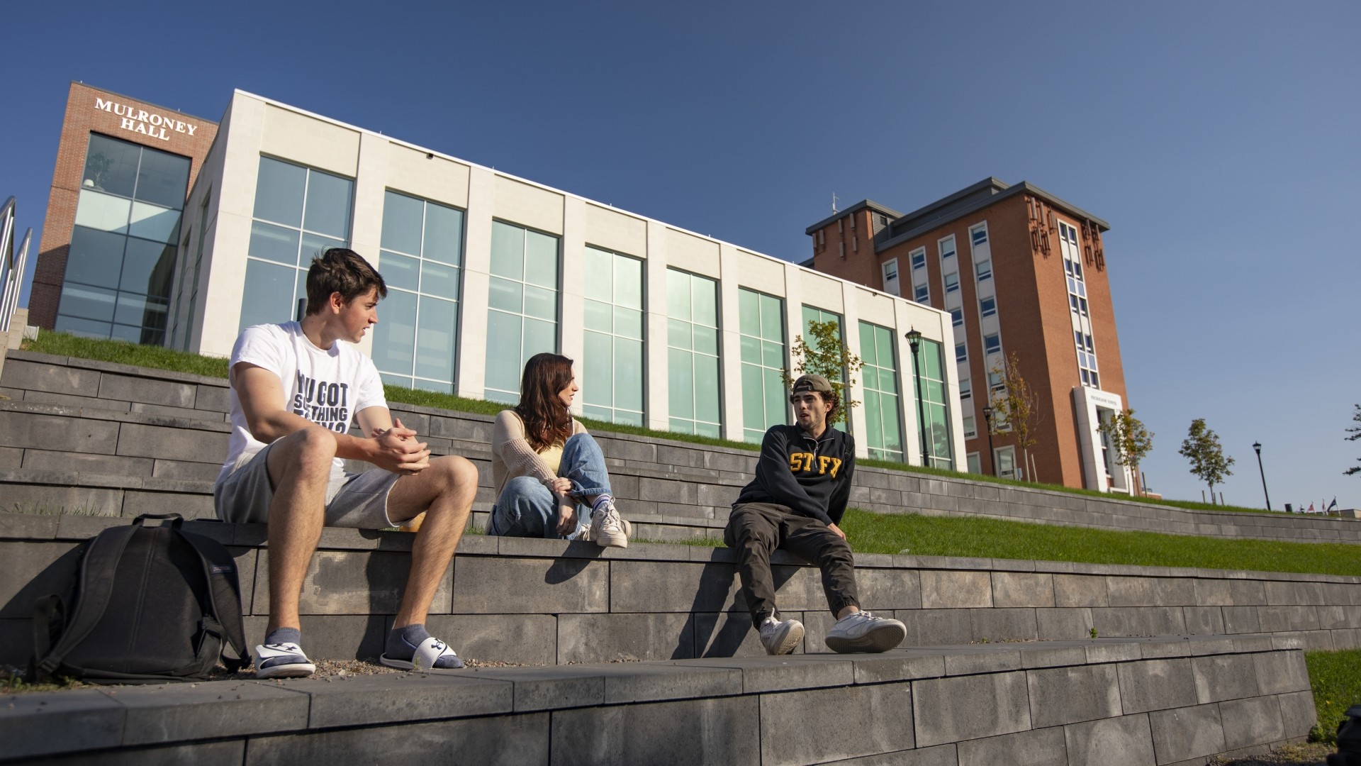 Students sitting on the brick located behind Mulroney Hall on a sunny day at a Canadian university