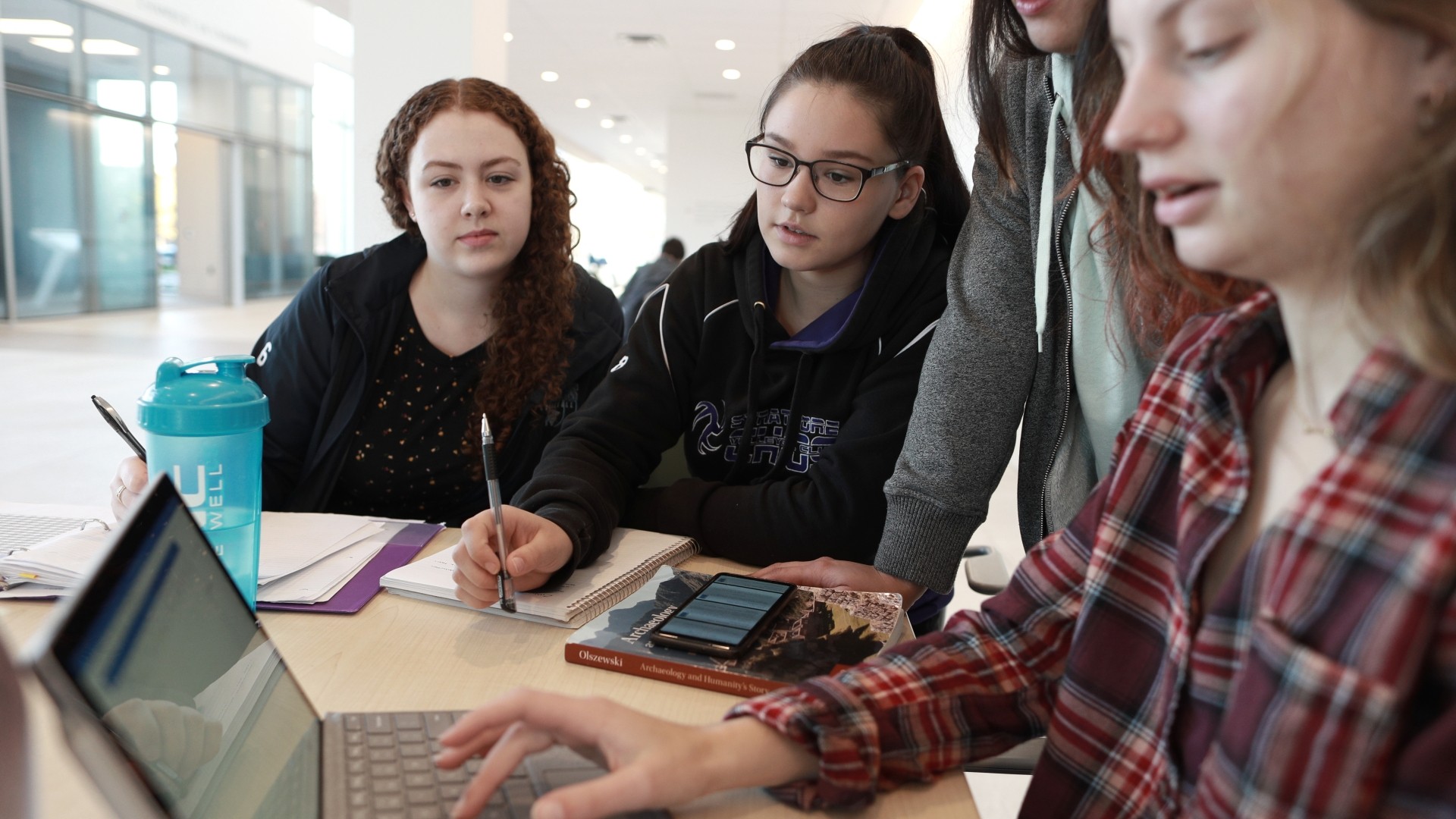 Close up of students studying at a table on the second floor of Mulroney Hall.