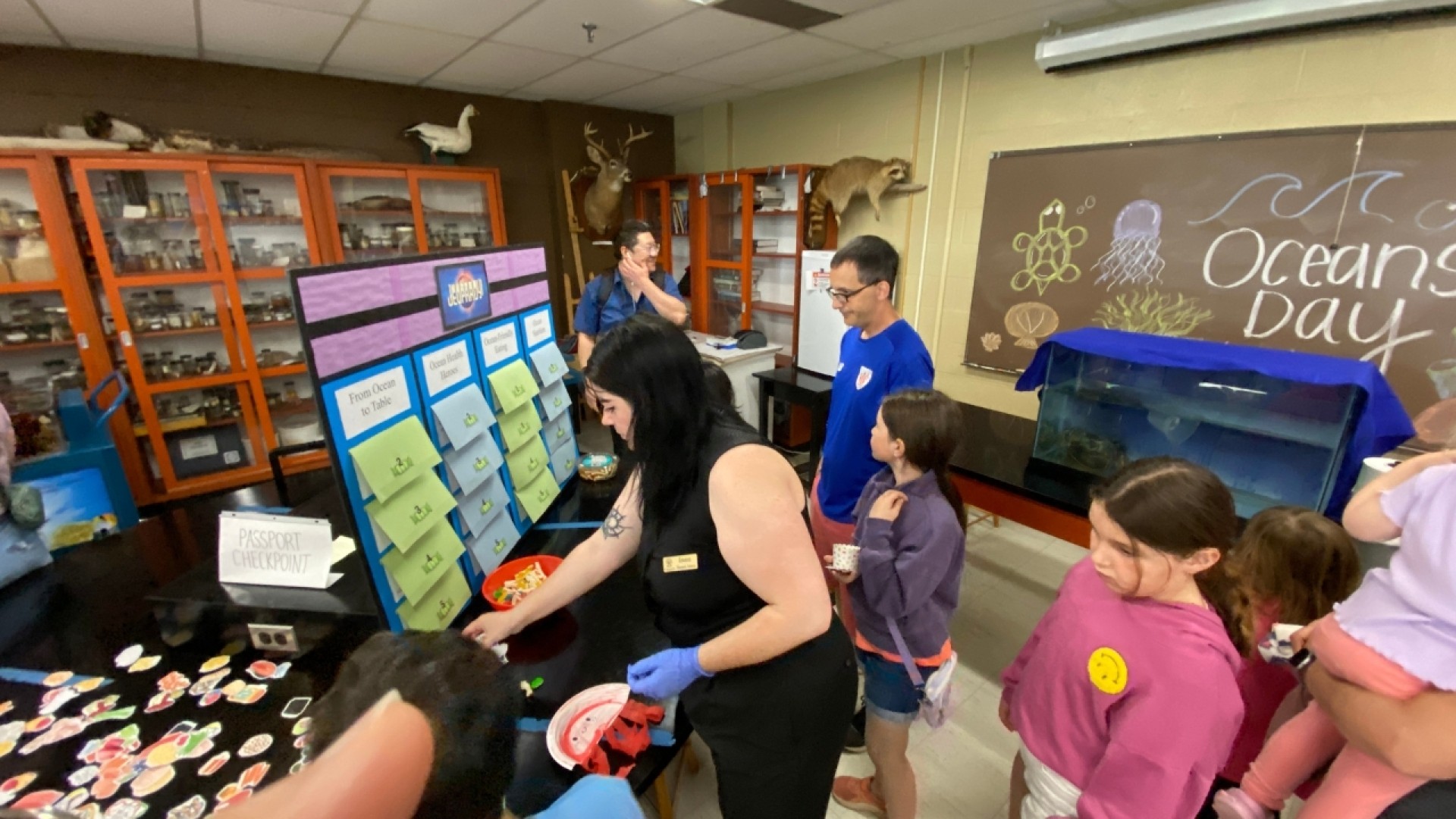 Children and adults in a classroom participating in an 'Oceans Day' activity with a numbered board and marine-themed decorations.