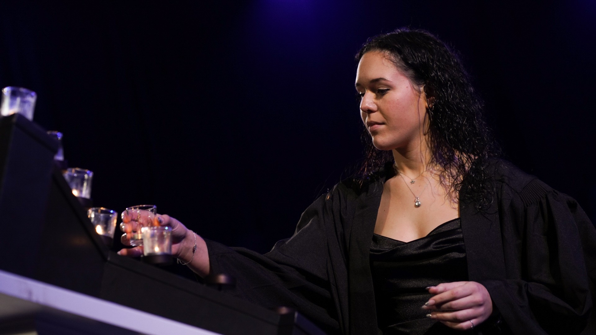 Student lighting the X Candle