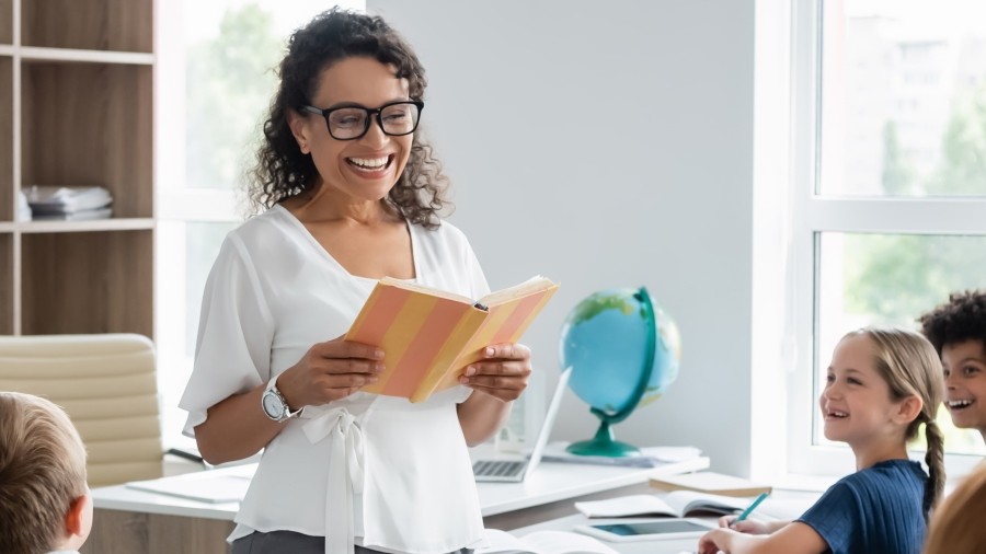 Teacher reading a book to young students in class