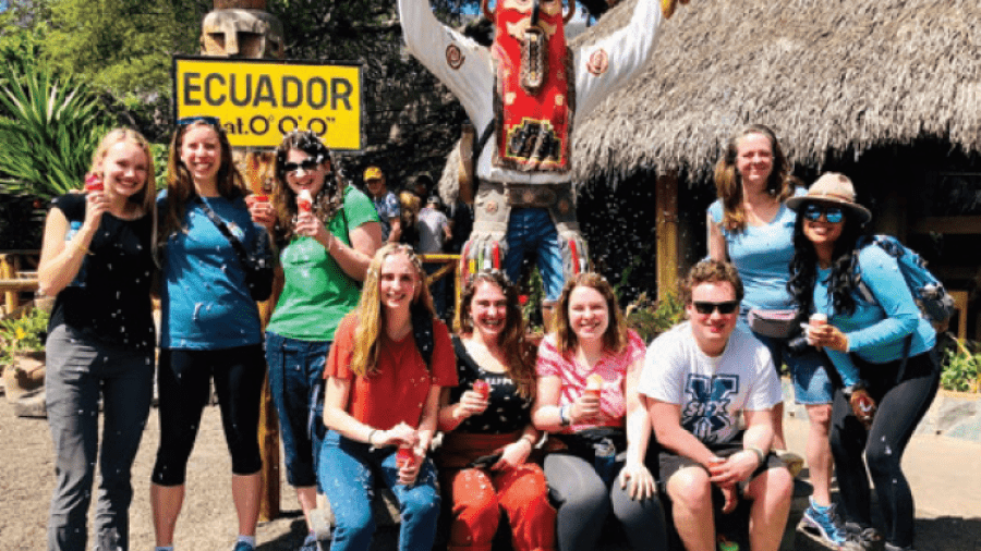A group of people by a grass hut in Ecuador