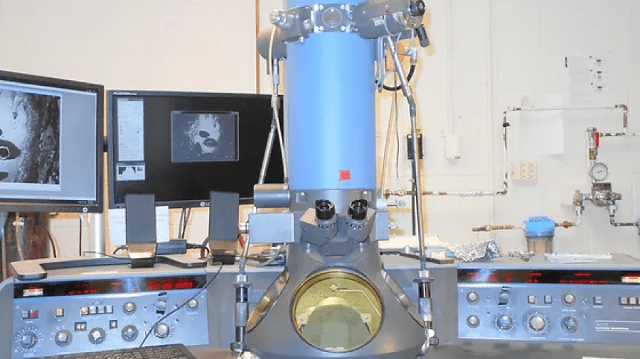 Image of a microscope on a table with equipment and screens