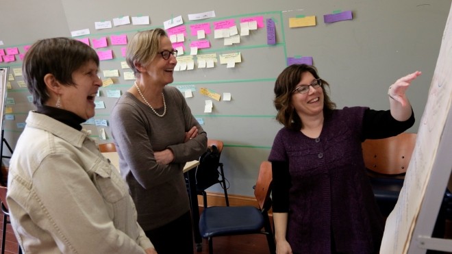 Pictire of a Program Graduate Teaching or Exposing to 2 Elderly People Using Whiteboard