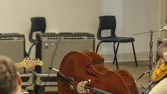 Instruments and equipment in a rehearsal space for students in the StFX Bachelor of Arts in Music program, featuring a double bass and amplifiers.