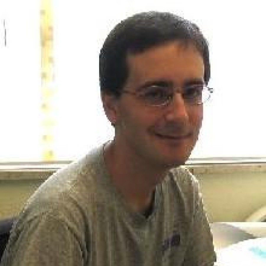 A man sitting at a desk in front of a laptop computer