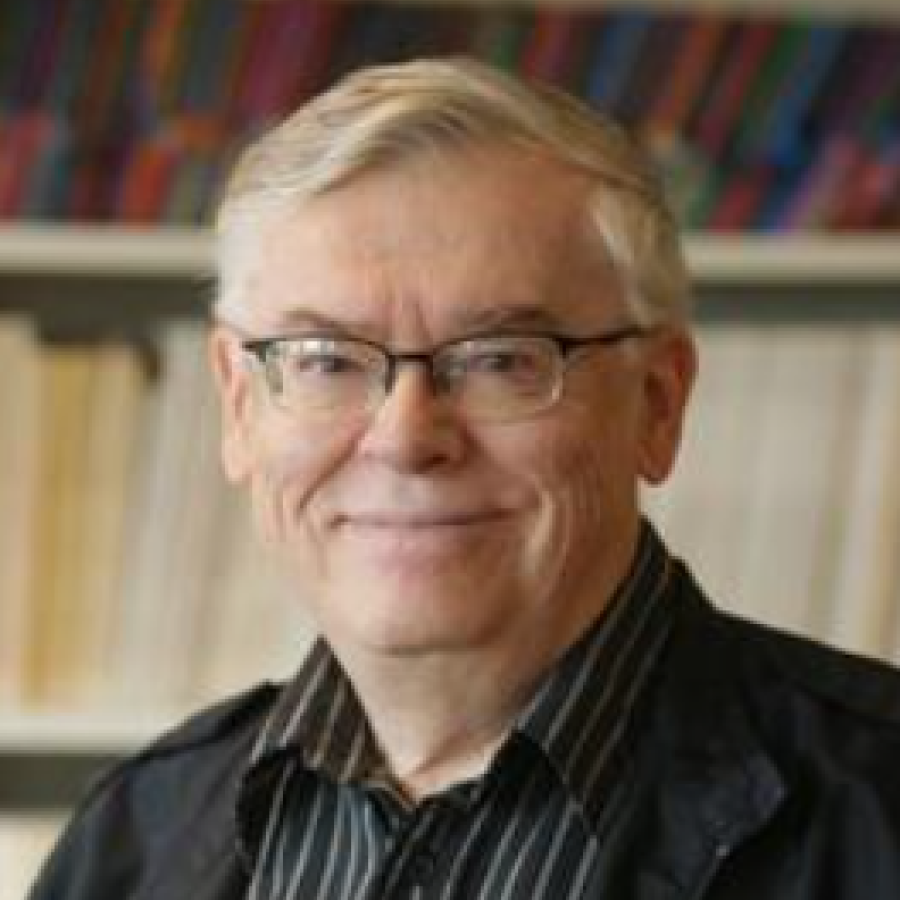 Headshot of a man standing behind a bookshelf 