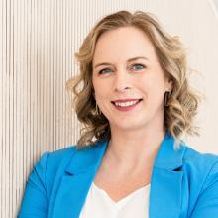 A woman in a blue jacket leaning against a wall