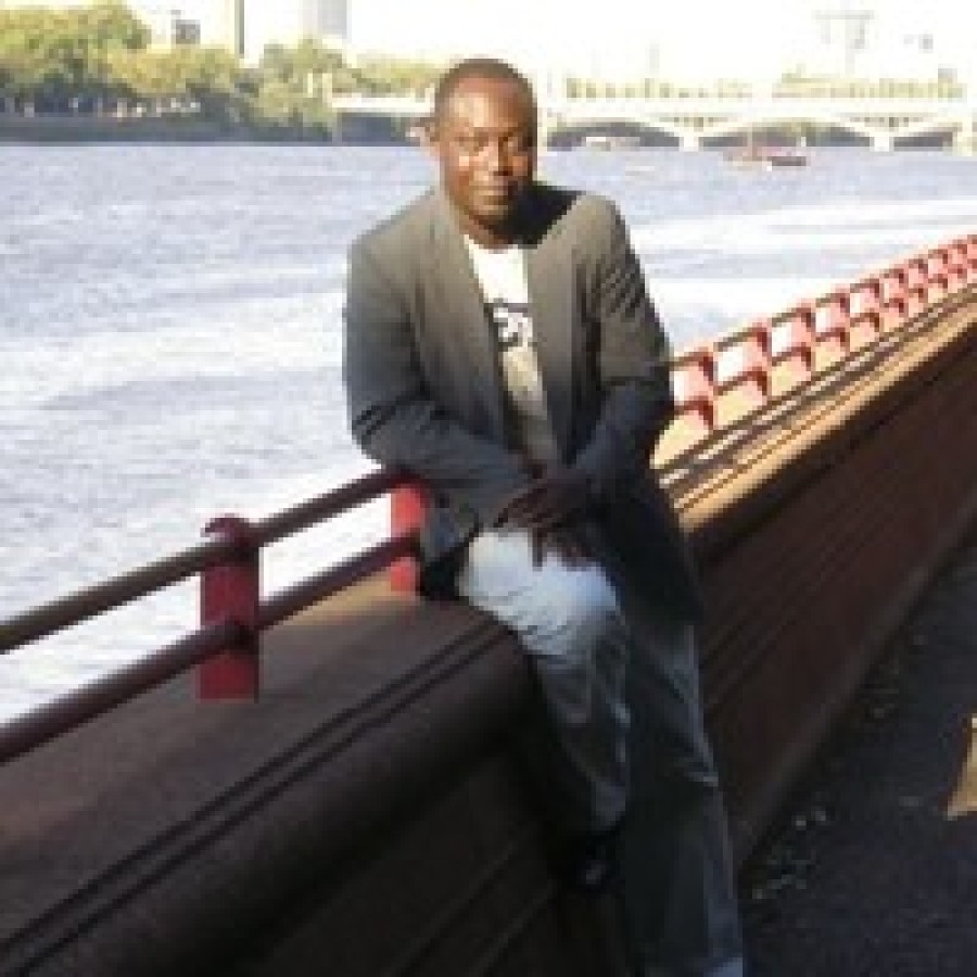 Person leaning on bridge in front of water