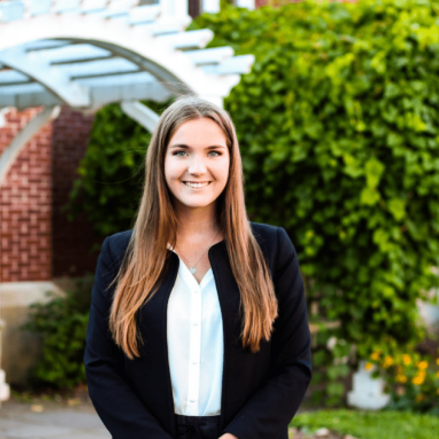 Smiling person dressed smartly standing in front of building