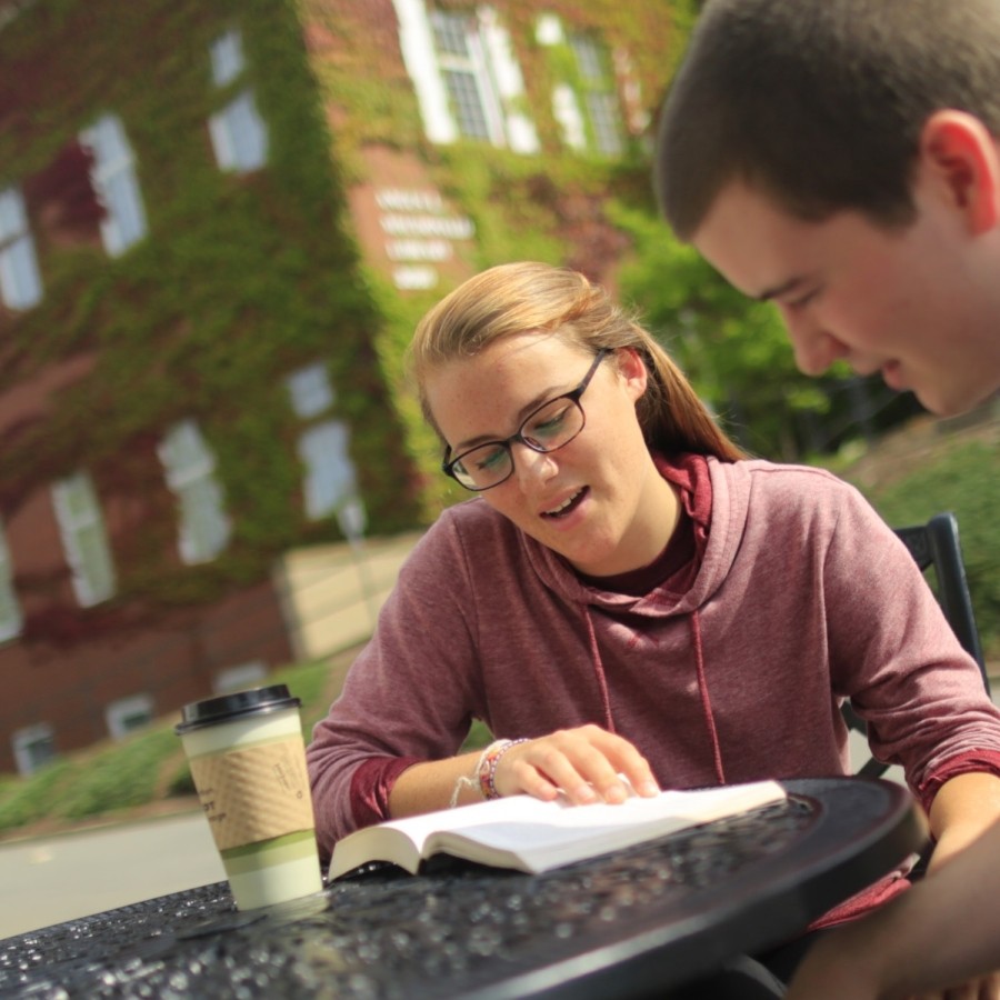  A man and woman sitting at a table reading a book