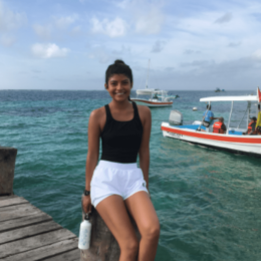 Girl sitting on boardwalk with a boat in the background 