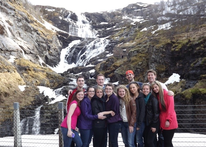 A group of people standing in front of a waterfall"
