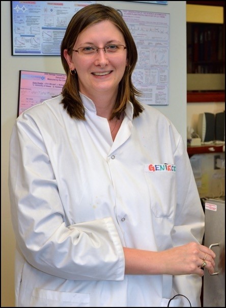 A woman in a white lab coat is smiling