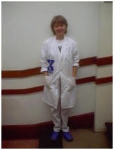 A man in a white suit standing in front of a wall