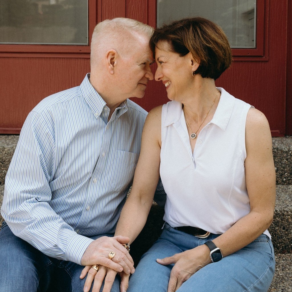 A couple holding hands and smiling at each other affectionately