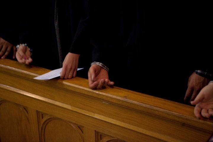 People tapping their X-rings on a church pew