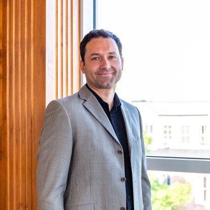 Person smiling standing next to window