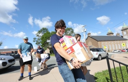A student and family members carrying boxes into residence