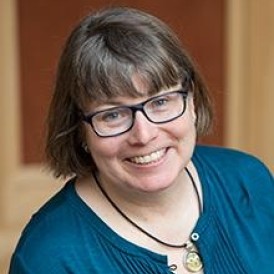 A woman with glasses is smiling for the camera