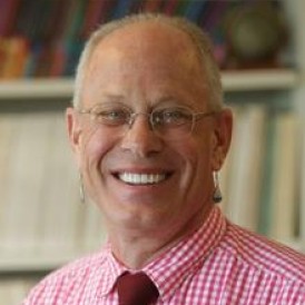A person in front of a bookcase smiling