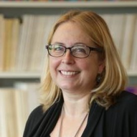 A person in front of a bookcase smiling